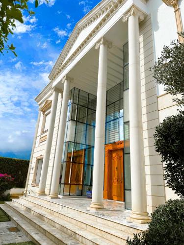a white house with columns and a wooden door at L'Orchidée - Suites de Luxe avec Piscine Chauffée et Vue sur le Lac de Tunis in Tunis