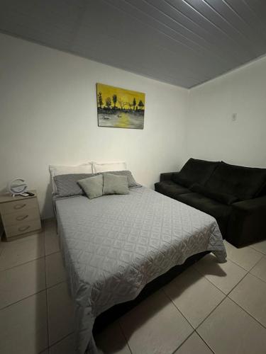 una camera da letto con un letto e un divano di Suítes privativas a Cachoeiras de Macacu