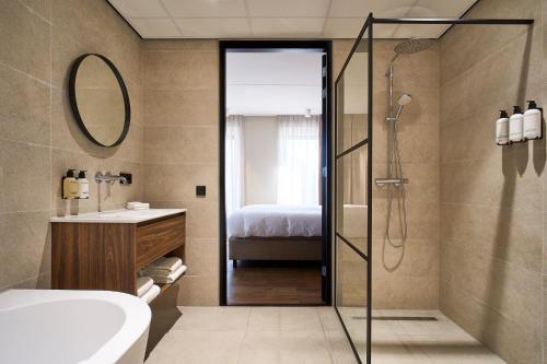 a bathroom with a shower and a sink and a tub at Eilandhotel Texel - Nieuw geopend hotel in De Cocksdorp