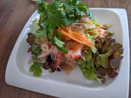 a white plate with a salad on a table at Kaeda Terrace - Vacation STAY 69516v in Miyazaki