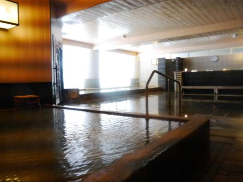 a room with a pool of water on the floor at Biei Shirogane Onsen Hotel Park Hills in Biei