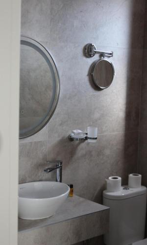 a bathroom with a sink and a mirror and a toilet at Old Stone Hotel Skopje in Skopje