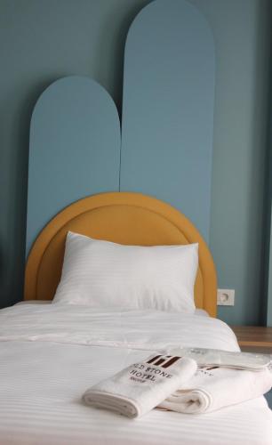 a bed with a wooden headboard and two towels on it at Old Stone Hotel Skopje in Skopje