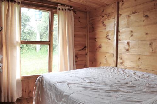 a bedroom with a bed in front of a window at LINDA CABAÑA HERMOSA VISTA NATURALEZa in Suesca