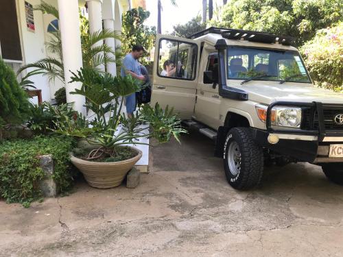 a man standing next to a truck with a plant at El Tessa garden/serviced apartment in Kisumu