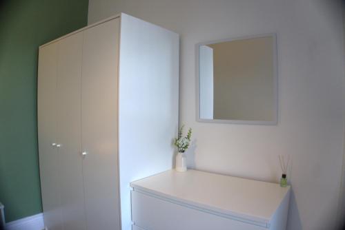a white cabinet with a mirror and a vase on it at 3BDR Town House in the Heart of Holyhead - Free Onsite Parking in Holyhead
