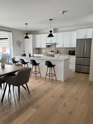 a kitchen with white cabinets and a table and chairs at Le 800 de St-Jovite in Mont-Tremblant