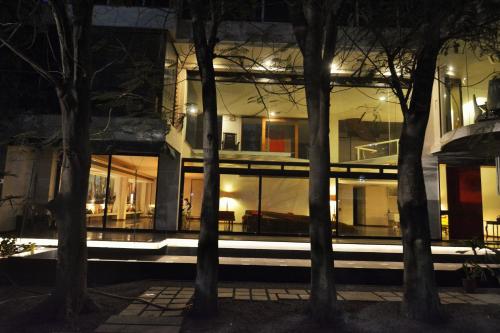 a building at night with trees in the foreground at The Sky Imperial Aarivaa Luxury Stays in Rajkot