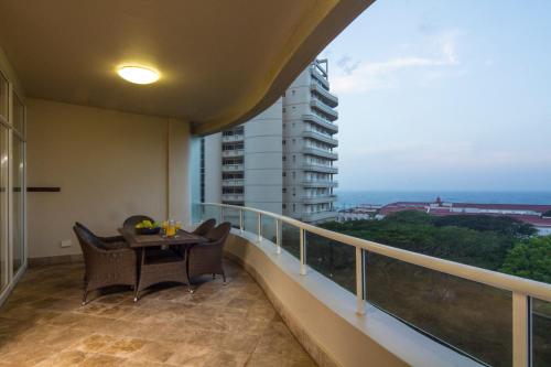 un balcón con mesa y sillas y un edificio en 203 Oyster Quays - by Stay in Umhlanga en Durban