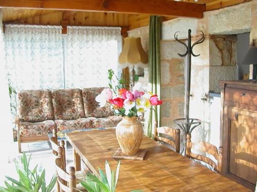 a living room with a table with a vase of flowers on it at Hameau les Combelles in Martel