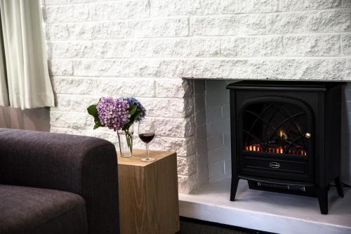 a fireplace with a stove and a glass of wine at Tall Trees Motel Mountain Retreat in Mount Tamborine