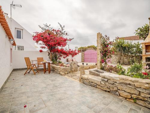 a patio with a table and a stone wall at Casa das bonecas in Pernigem