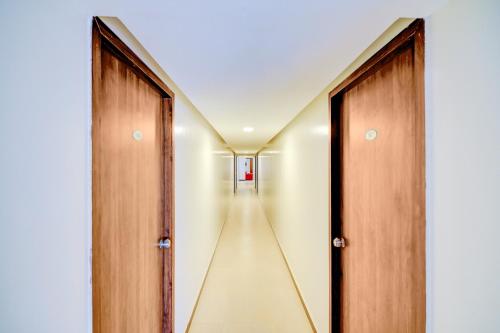 a hallway with two wooden doors and a long corridor at Hotel O Peaceful Stay Keshav Nagar. in Kharadi