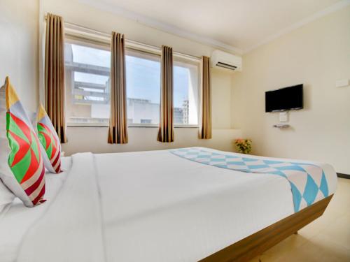 a bedroom with a large white bed with a window at Hotel O Peaceful Stay Keshav Nagar. in Kharadi