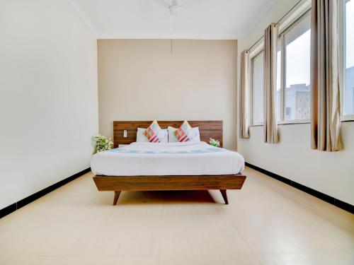 a bedroom with a bed with white sheets and windows at Hotel O Peaceful Stay Keshav Nagar. in Kharadi