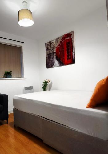 a bed in a room with a red phone booth on the wall at 1 private room & a toilet in 2bed apartment in Manchester