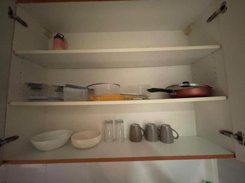a shelf with bowls and utensils in a kitchen at Ultra Luxury Chic Studio in JLT in Dubai