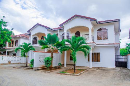 a white house with palm trees in front of it at Heavenly Homes in Malindi