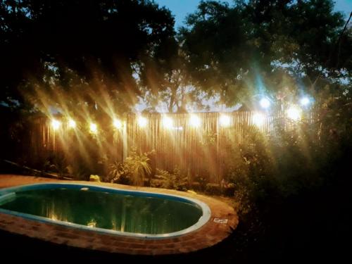 a swimming pool at night with lights on a fence at Cabañas Carayá II in Paso de la Patria