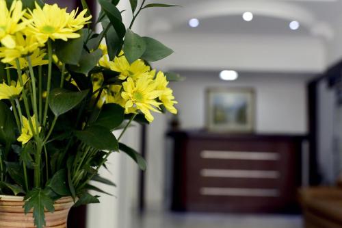 a vase filled with yellow flowers in a room at Apartaestudios Granada in Cali