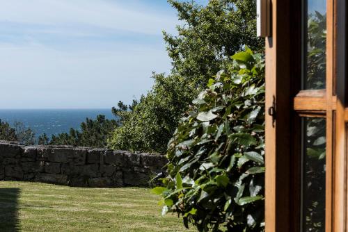 a window view of a stone wall and the ocean at LUXURY CELAVELLA GALICIA Hc in Baiona