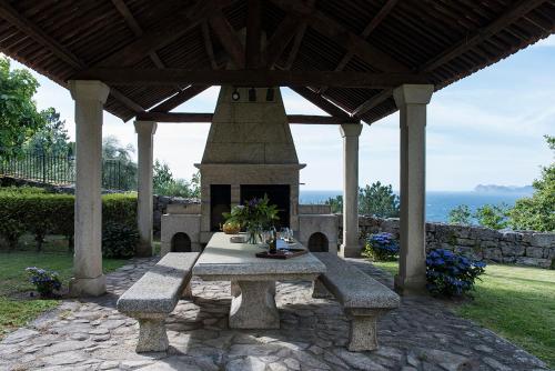a picnic table under a gazebo with a fireplace at LUXURY CELAVELLA GALICIA Hc in Baiona