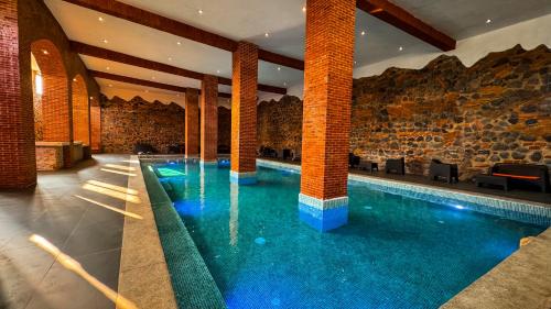 a swimming pool in a building with a stone wall at Le Suisse Spa in Santa Lucía Milpas Altas