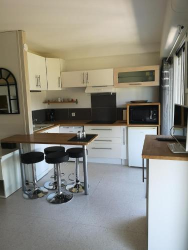 une cuisine avec une table et deux tabourets de bar dans l'établissement Appart bord de mer, piscine et clim, à Carnon-Plage