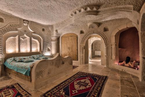 a bedroom with a bed and a person sitting in a fireplace at The Village Cave Hotel in Göreme