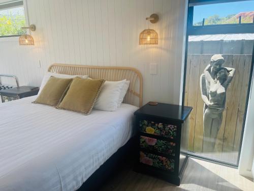 a bedroom with a bed with a picture of a man holding a baby at Matakana Central 981 in Matakana