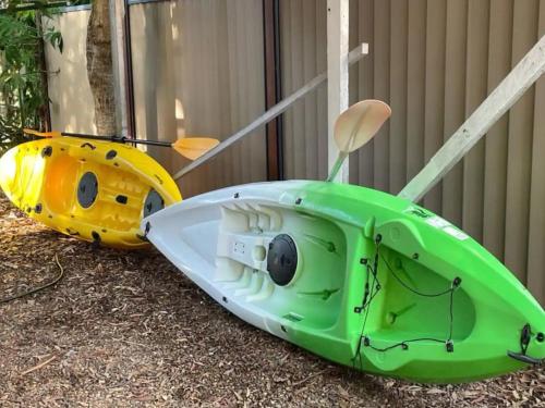 a green kayak and a yellow boat on the ground at Pet friendly beachfront home- sleeps 8 in Toogoom