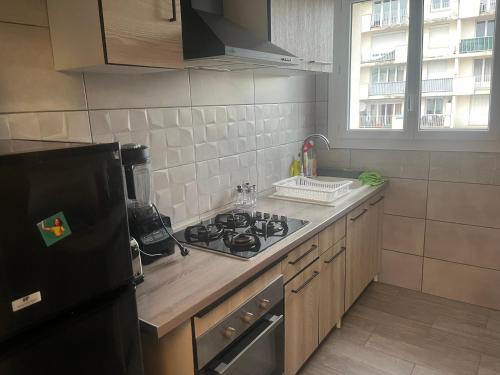 Il comprend une cuisine équipée d'une cuisinière et d'un réfrigérateur noir. dans l'établissement F4 Appartement 3 chambre avec wifi, à Saint-Jean-de-la-Ruelle