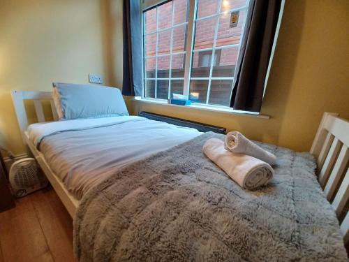 a bed in a room with a window and two towels at The Marshmallow in Grays Thurrock