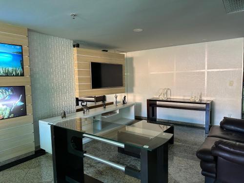 a living room with a couch and a tv at Arraial do cabo loft prainha in Arraial do Cabo