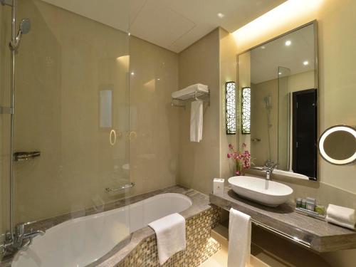 a bathroom with a tub and a sink and a mirror at Gulf Executive Residence in Manama