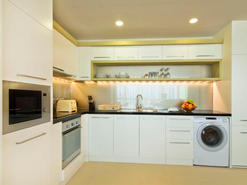 a white kitchen with a sink and a dishwasher at Gulf Executive Residence in Manama