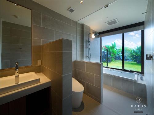 a bathroom with a sink and a toilet and a window at BATON SUITE Okinawa-kourijima in Nakijin