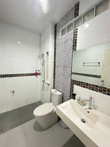 a white bathroom with a toilet and a sink at PN Home in Ban Kota