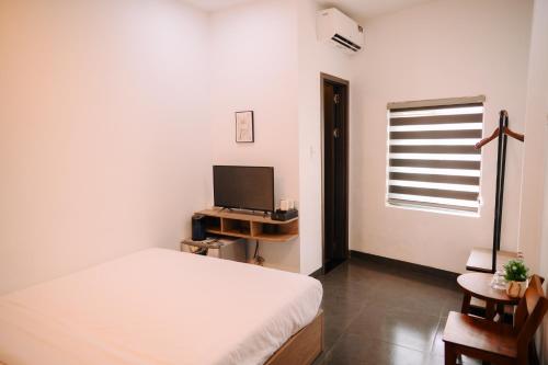 ein Schlafzimmer mit einem Bett und einem Flachbildfernseher in der Unterkunft Charm House Hue in Hue