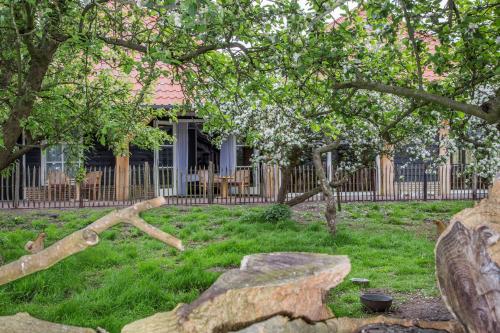 a house with a fence and a yard with a tree at Hotel Hof van 's Gravenmoer in 's-Gravenmoer