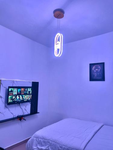 a white bedroom with a bed and a light fixture at Dersym Apartment in Port Harcourt