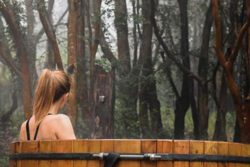 a woman sitting on a bench in a forest at NI-NEWEN Hotel & Lodge in Pucón