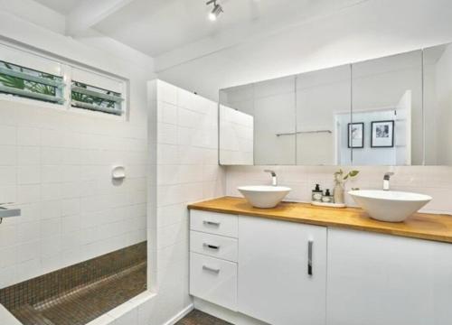 une salle de bain avec deux lavabos et des armoires blanches dans l'établissement Palm Springs Bungalow, à Trinity Beach
