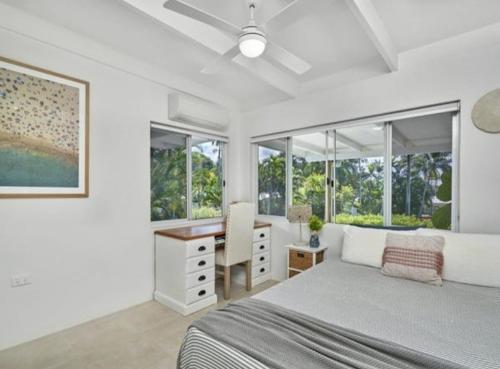 une chambre avec un lit, un bureau et des fenêtres dans l'établissement Palm Springs Bungalow, à Trinity Beach