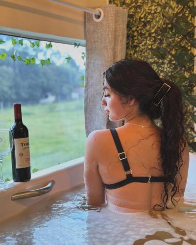 a woman in a bathtub with a bottle of wine at Pousada Quinta das cores in Urubici