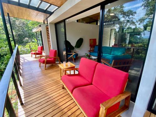 a living room with a red couch on a deck at Sinfonía Tropical, ocean view, 5 minutes driving to Playa Linda, 15 to Dominical, wifi Starlink in Savegre