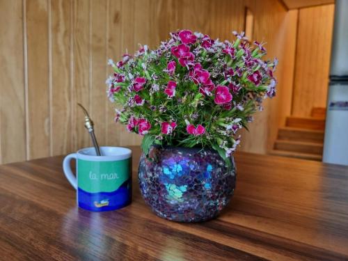 a vase filled with flowers next to a coffee mug at Departamentos Atardecer in Natuco