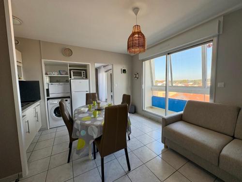 une cuisine et un salon avec une table et un canapé dans l'établissement Appartement rénové à Saint-Hilaire-de-Riez, parking privé, proche plage et commerces - FR-1-323-258, à Saint-Hilaire-de-Riez
