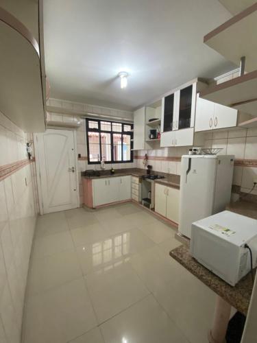 a large kitchen with white cabinets and appliances at Casa em Itapuã pertinho da praia in Vila Velha