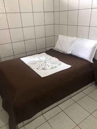 a bed with a white blanket on top of it at Hotel Redentor GV in Governador Valadares